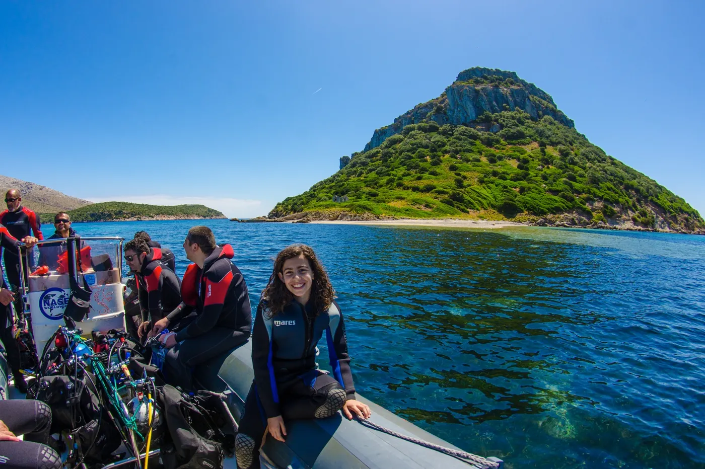 l'isola di Figarolo vista da Cala Moresca, con varie persone su un gommone in primo piano