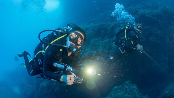 una subacquea sorride alla fotocamera durante un'immersione in coppia